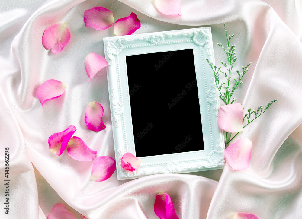 the Empty photo frame with a bouquet sweet pink roses  petal on  soft pink silk fabric , romance and