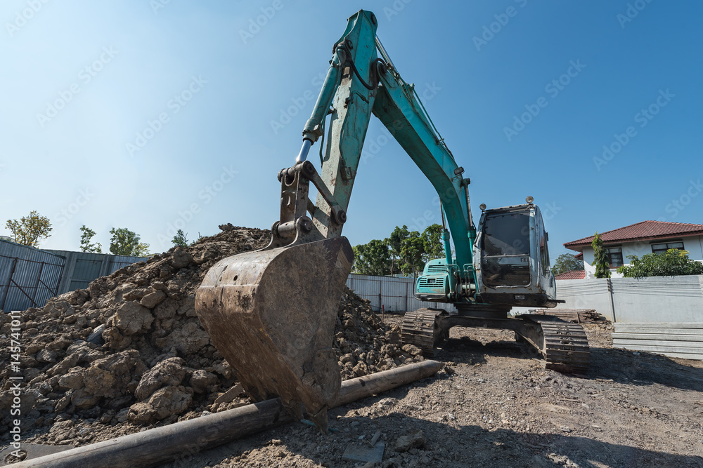 excavator on construction site, digger on gravel heap with shovel