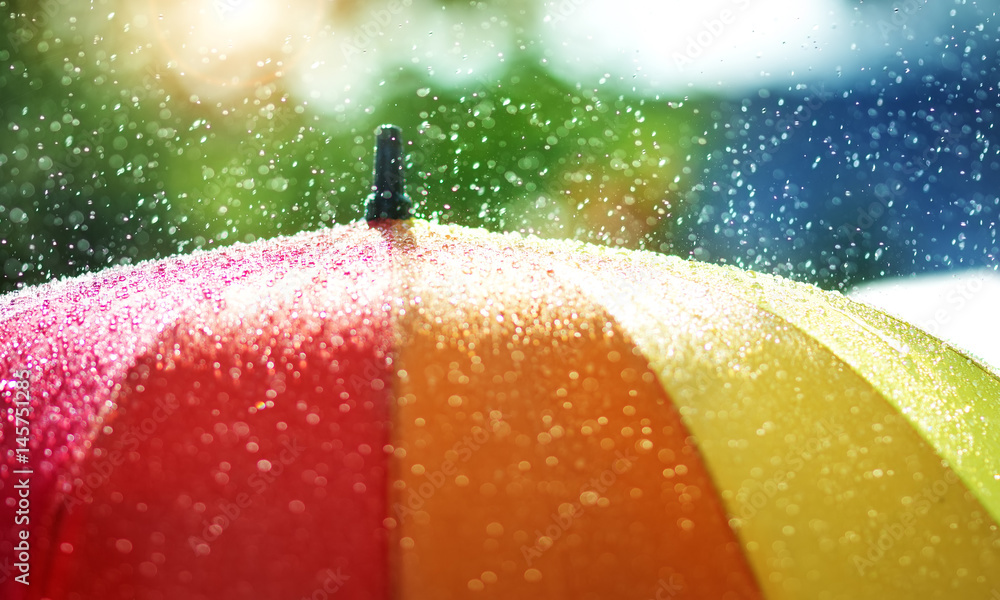 Rain drops falling onto umbella with rainbow colour- Rainy weather