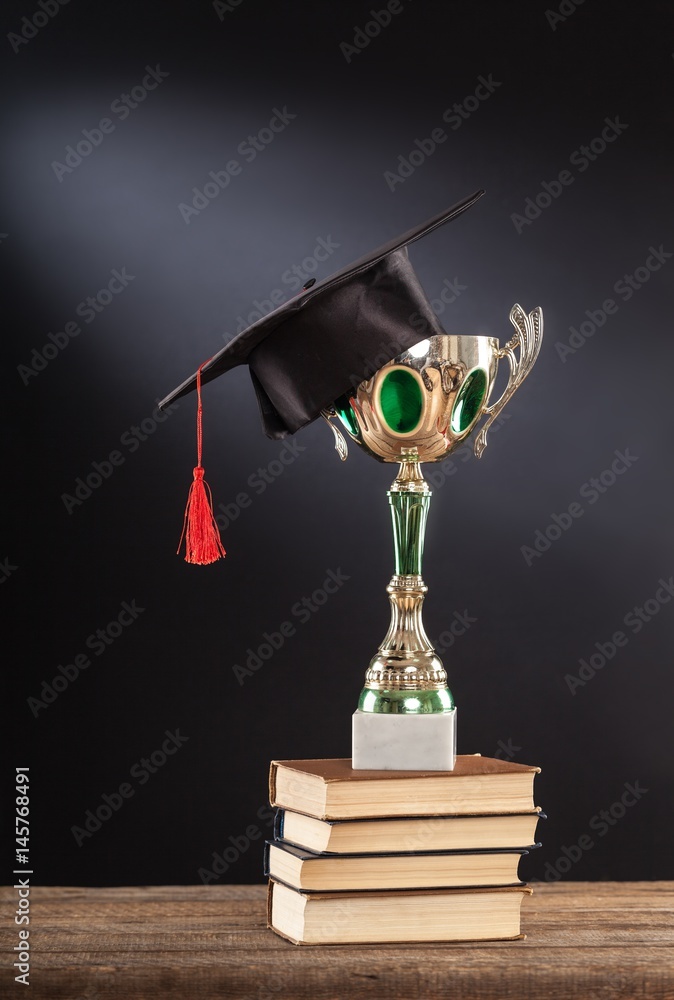 Graduation cap with champion golden trophy.