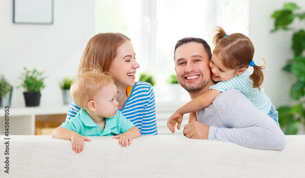 Happy family  laughing and hugging at home on sofa