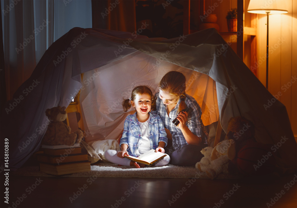 mother and child daughter with a book and a flashlight before going to bed