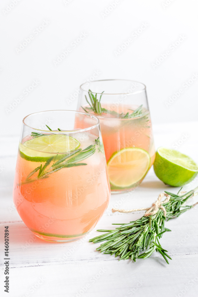 sliced lime, rosemary and natural juice in glass on white table background