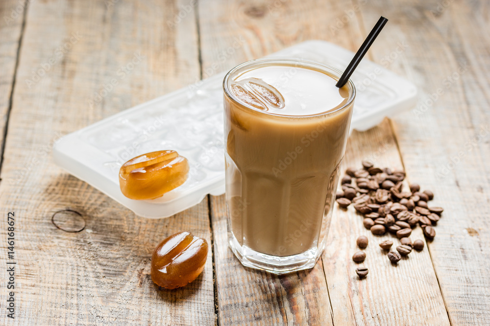 cold coffee glass with ice cubes on wooden table background