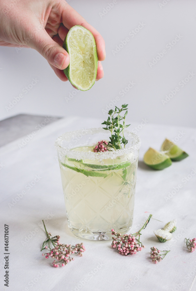 sweet fresh cocktail with flowers and cut lime on stone desk background