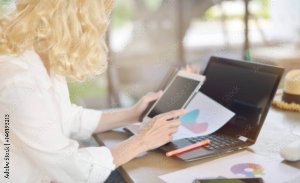 Blurred businesswoman working in office with laptop computer and documents