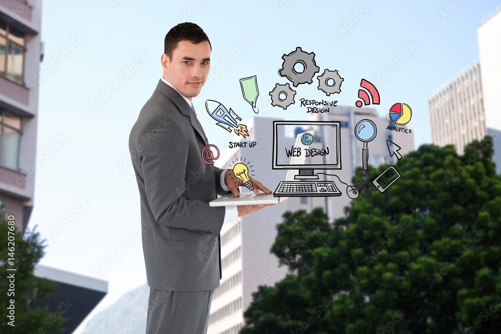 Confident businessman holding laptop by web design icons