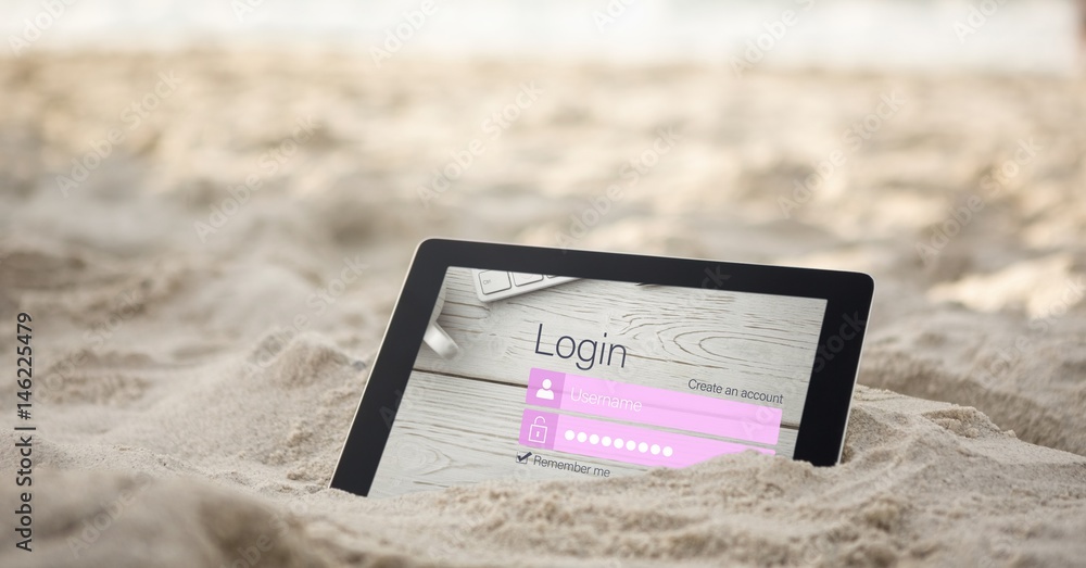 Digital tablet in sand with log in page on screen