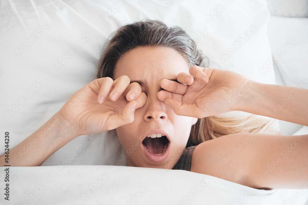 Donna sbadiglia a letto, sonno al mattino