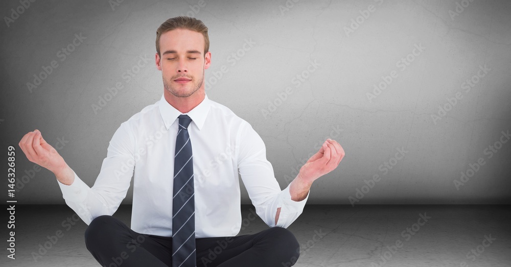 Business man meditating in grey room