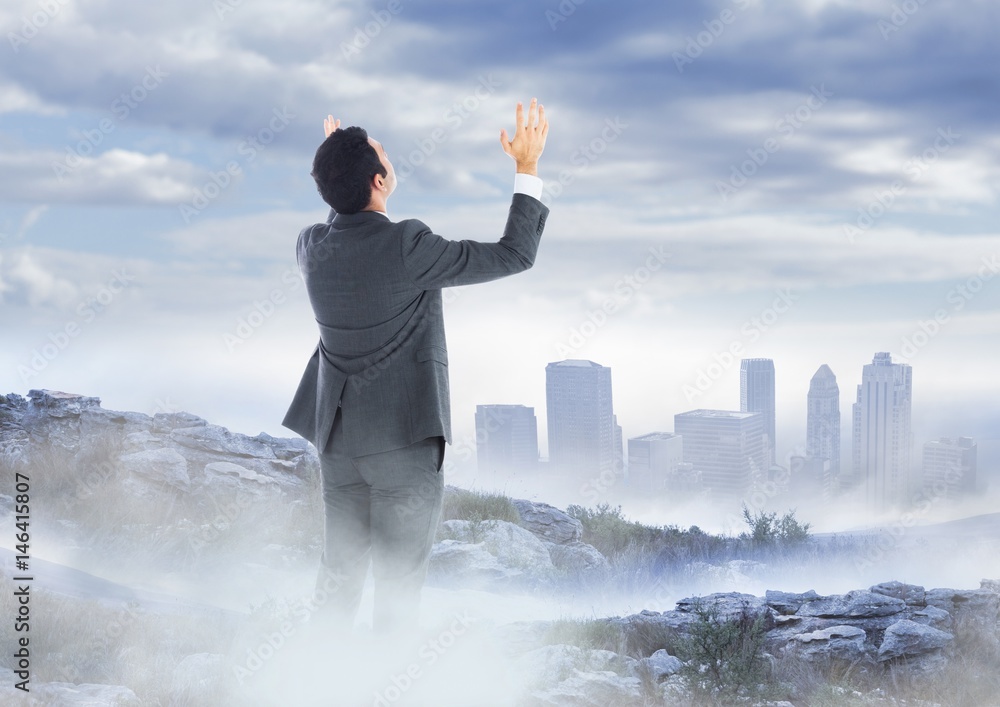 Business man hands up on misty mountain peak against skyline