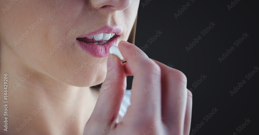 Woman taking pill against dark grey background