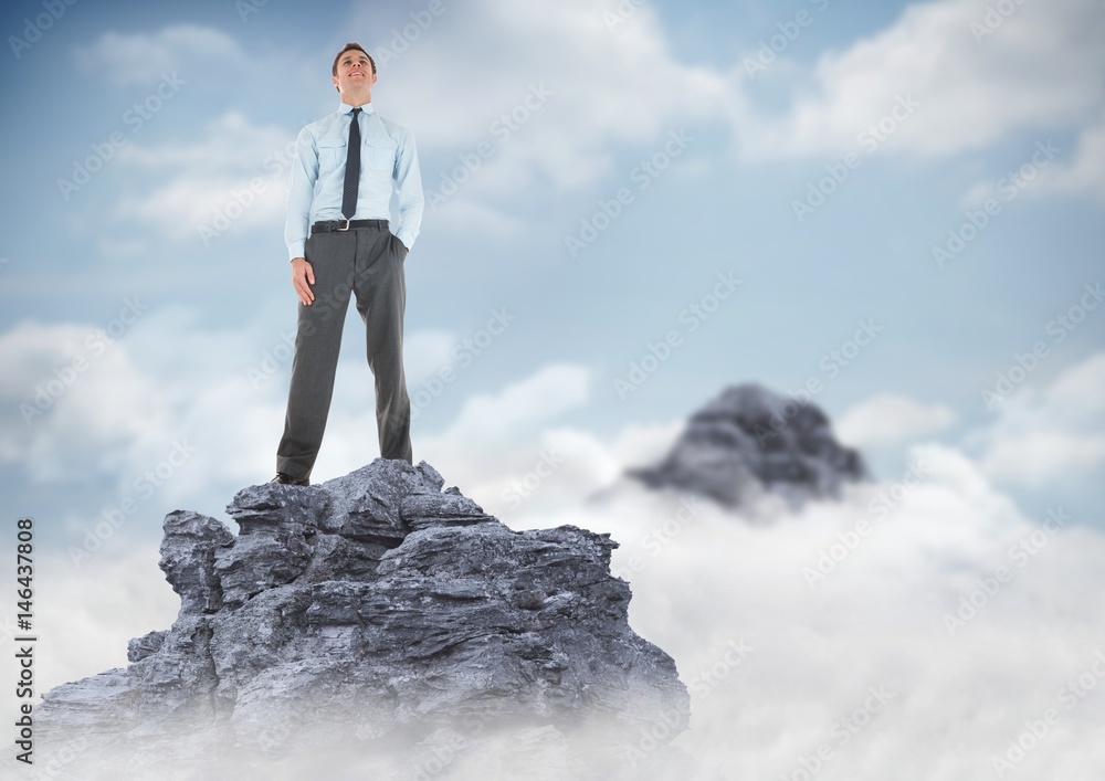 Business man hand in pocket on mountain peak in clouds