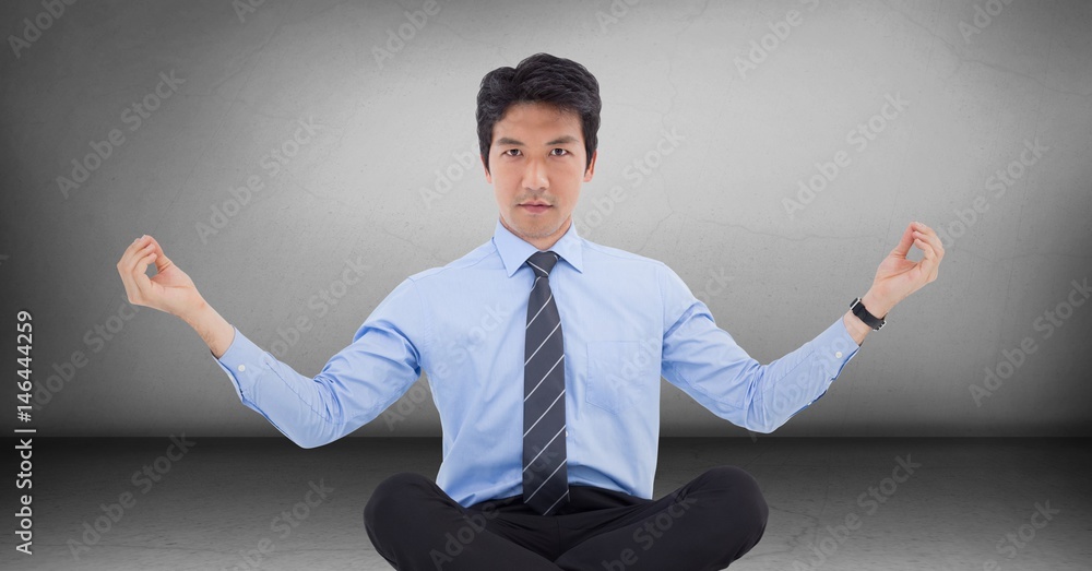 Business man meditating in grey room