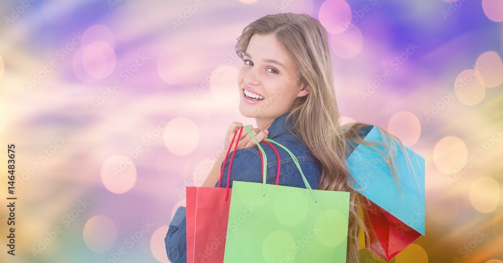 Smiling woman carrying shopping bags over bokeh