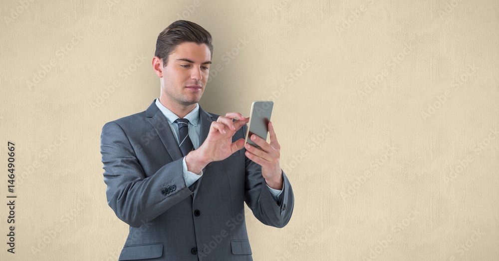 Handsome businessman using smart phone over beige background