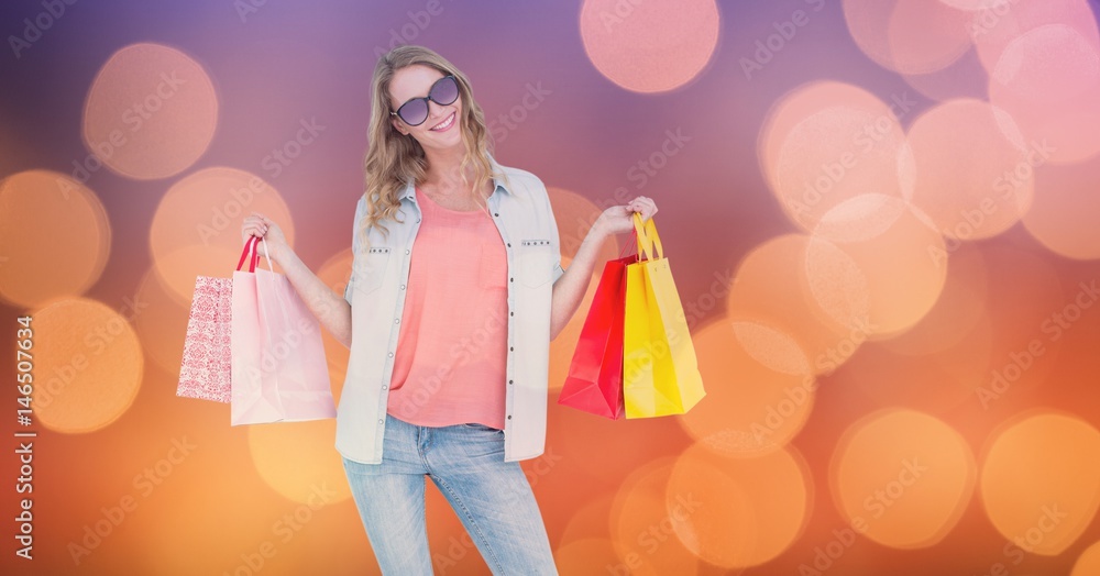 Fashionable woman holding shopping bags over bokeh