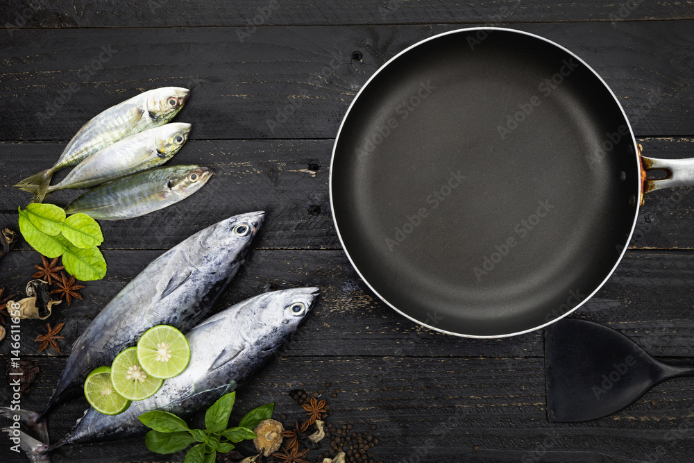 Fresh fish and black frying pan on dark black background, Fish with spices and vegetables, cooking b