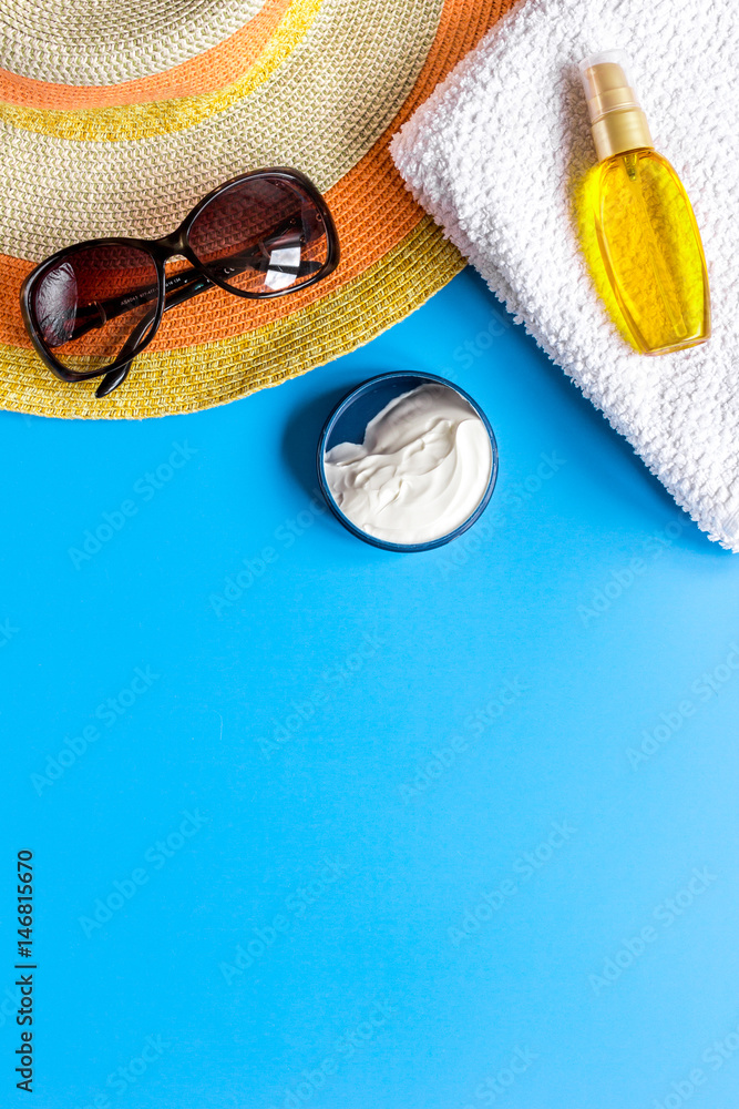 Summer cosmetic with protection cream and hat blue background top view mock up