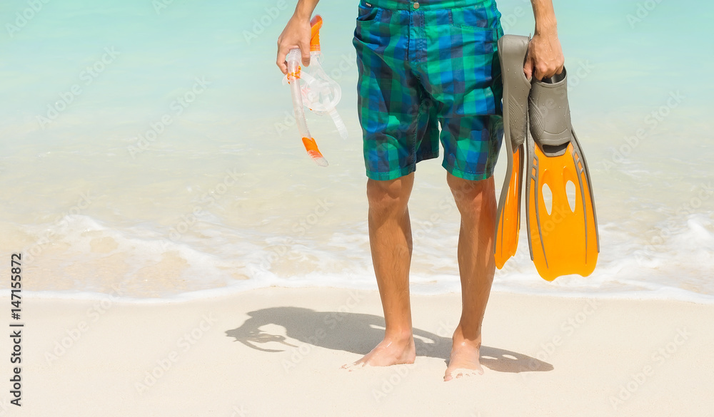 man holding mask and flippers for swimming on the ocean background