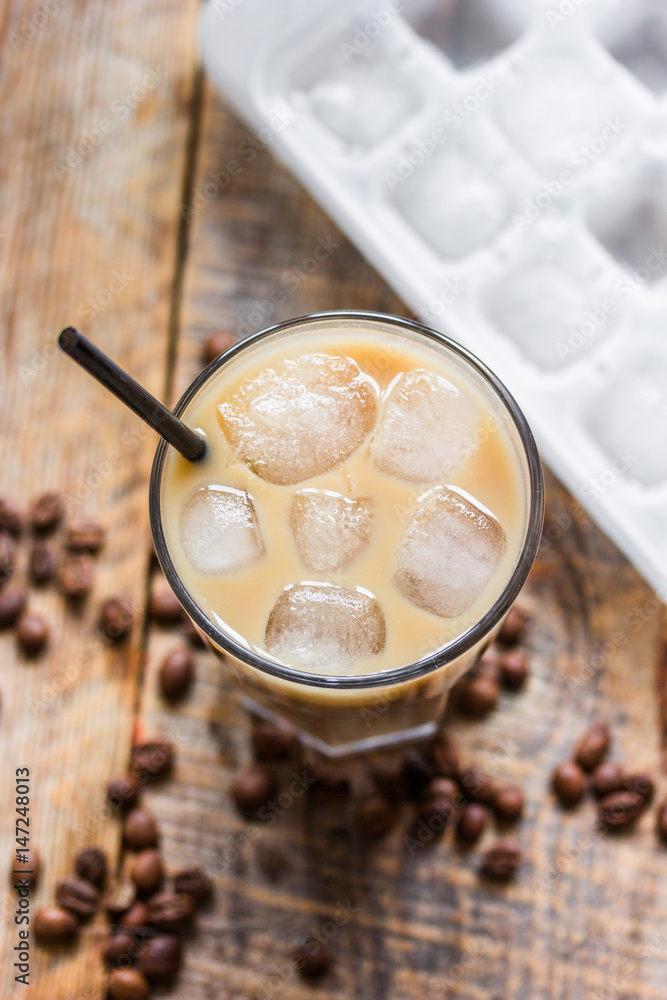 cold coffee glass with ice cubes on wooden table background