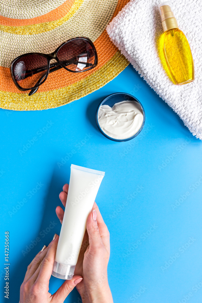 Sun glasses, protiction cream, hat, towel for beach rest blue background top view