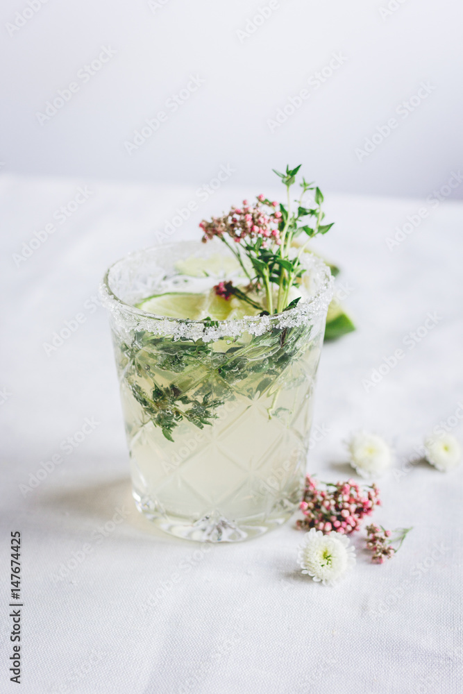 sweet fresh cocktail with flowers and cut lime on stone desk background