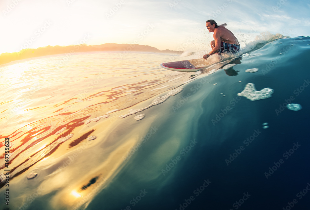 Surfer rides the perfect ocean wave at sunrise