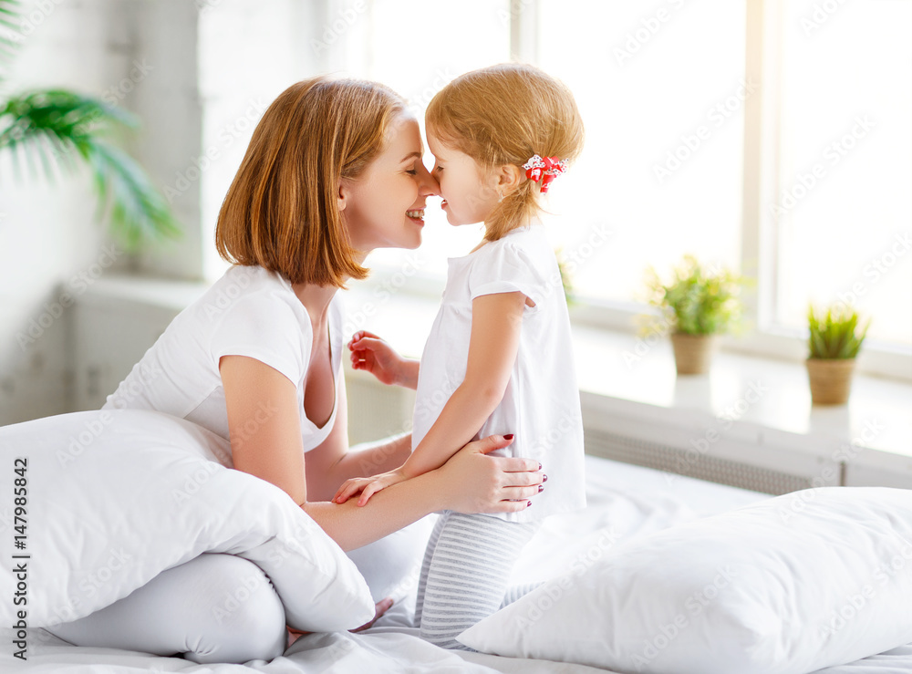 Happy family mother and child daughter laugh in bed