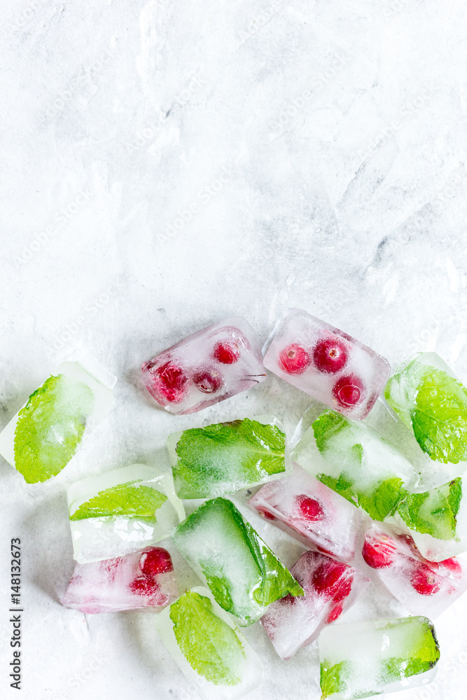 Ice cubes with berries and mint stone background top view mock up