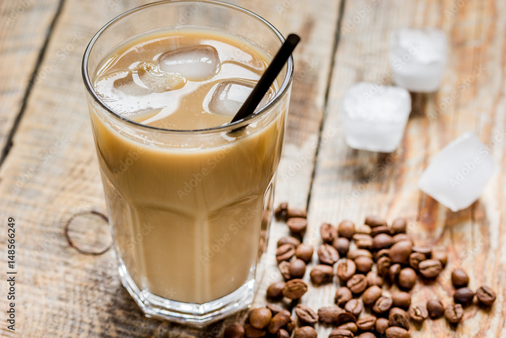 cold coffee glass with ice cubes on wooden table background