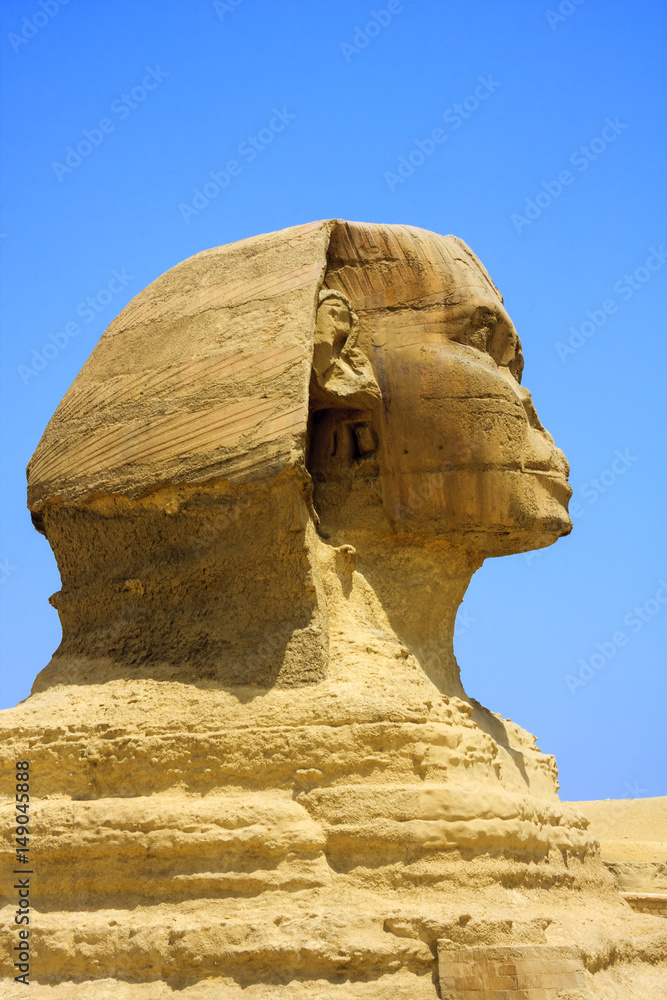 Close up of the face of the Great Sphinx with a set of pyramids in the background on a beautiful cle