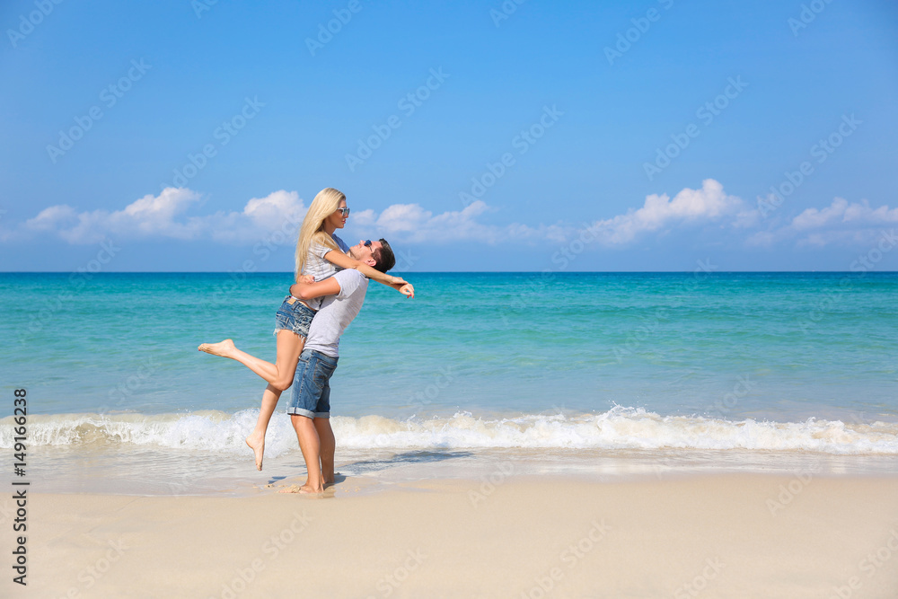 Young happy couple on beach smiling holding around each other. Love story