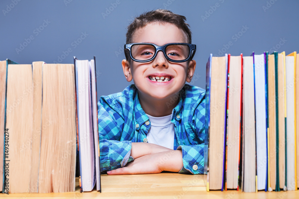 Happy pupil in glasses against books