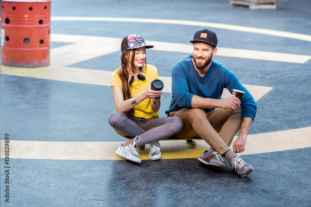 Stylish couple with skateboard outdoors