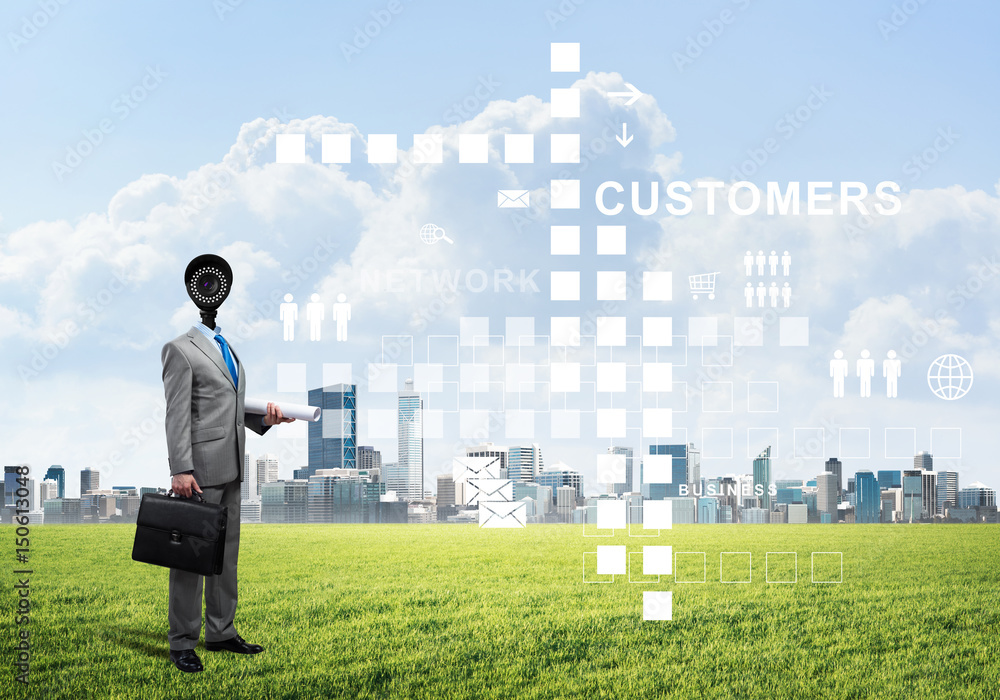 Camera headed man standing on green grass against modern cityscape