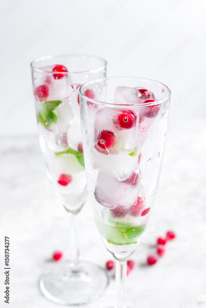 mint and red berries in ice cubes in glasses white background