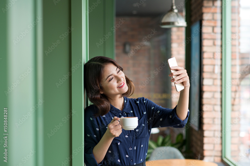 咖啡馆里漂亮可爱的亚洲年轻女商人，用手机自拍