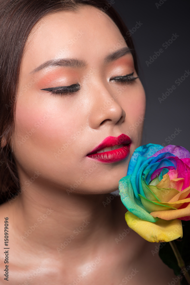 Beautiful asian woman face with perfect makeup with flowers of a rose