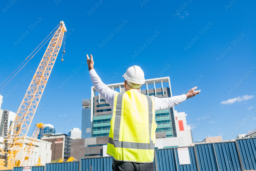 阳光明媚的日子里，戴着眼镜的高级工头在建筑区工作