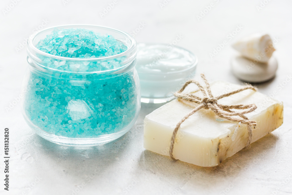 blue bath salt, body cream and shells for spa on white table background