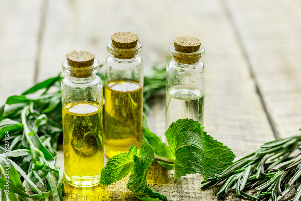 herbal extract in glass bottles, mint and rosemary for spa on wooden table background