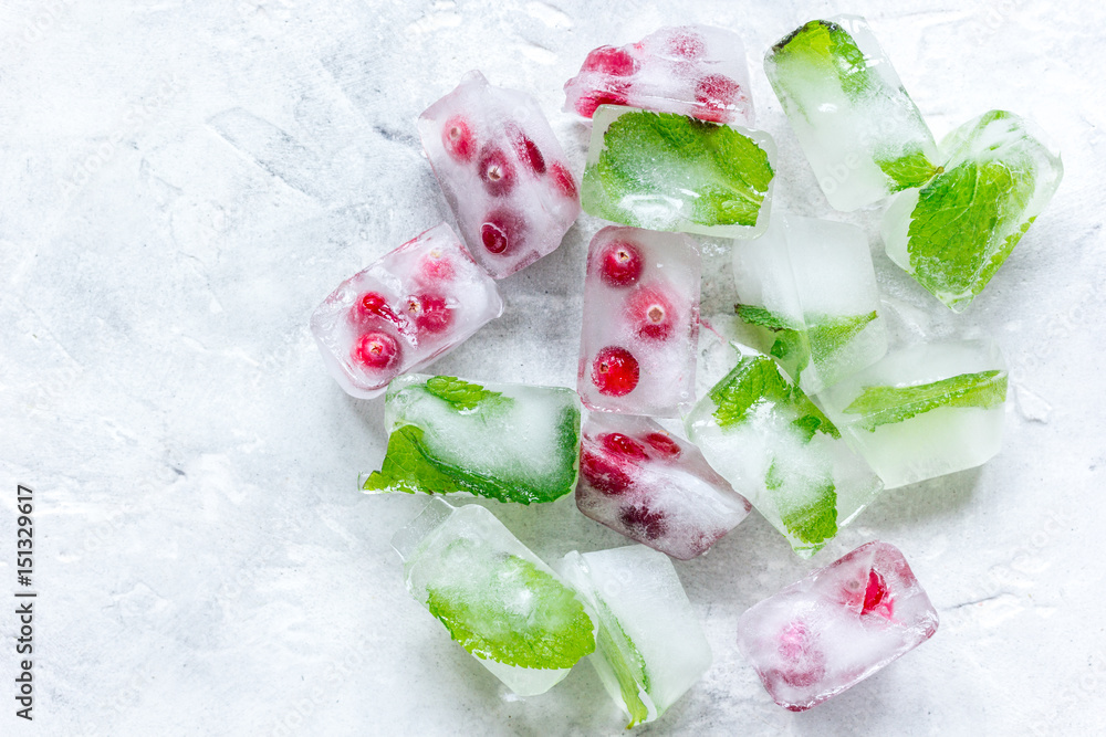 frozen red berries in ice cubes on stone background top view