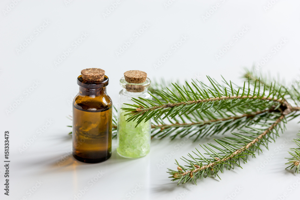 Spruce needle aromatherapy essential oils and salt in bottles on white table background