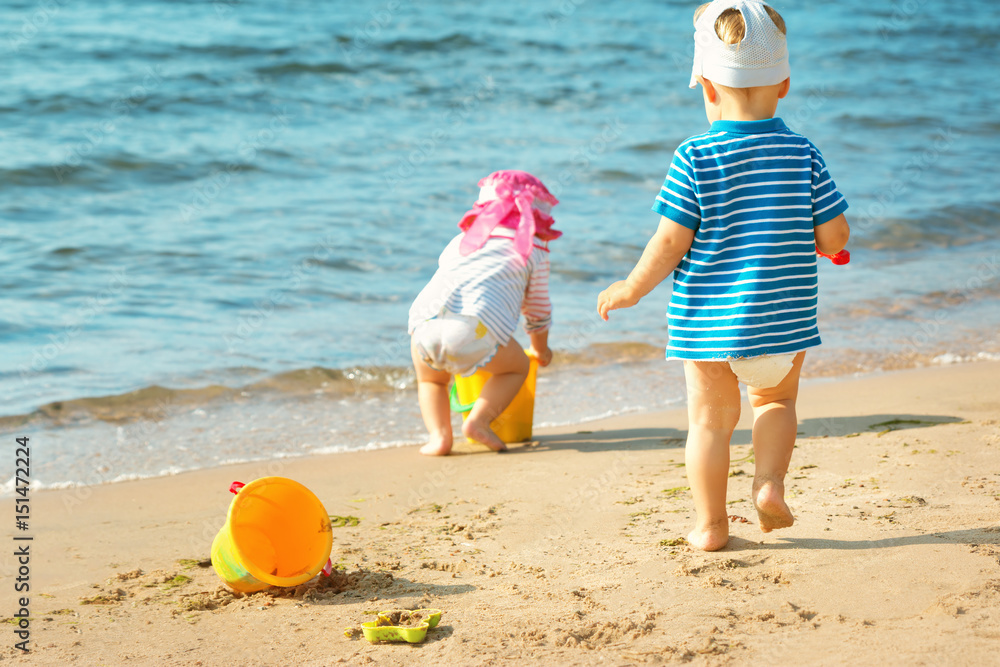 Babygirl and babyboy playing on the beach