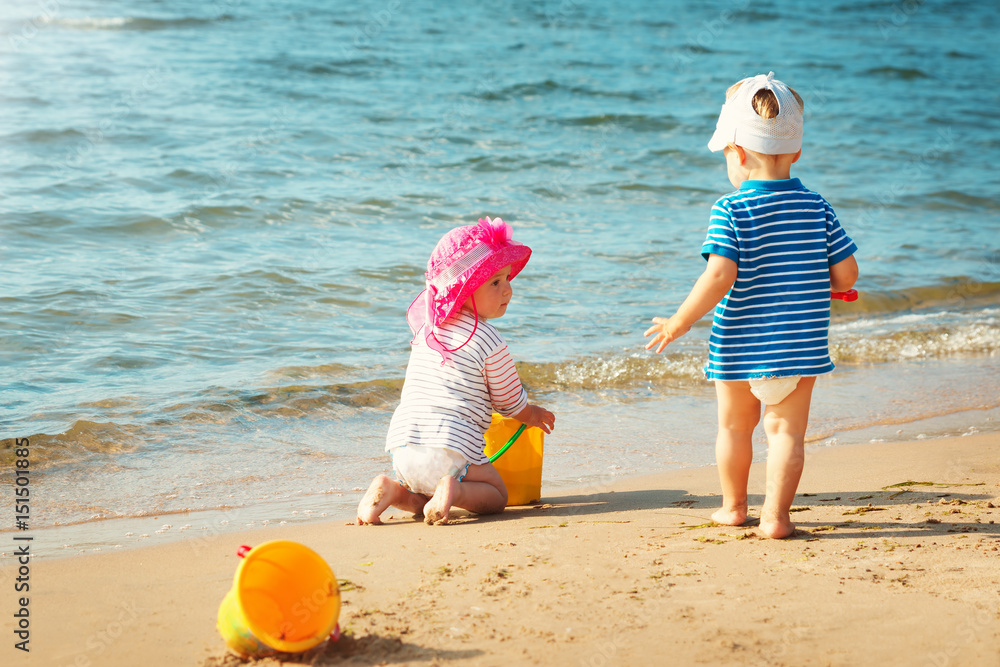 Babygirl and babyboy playing on the beach