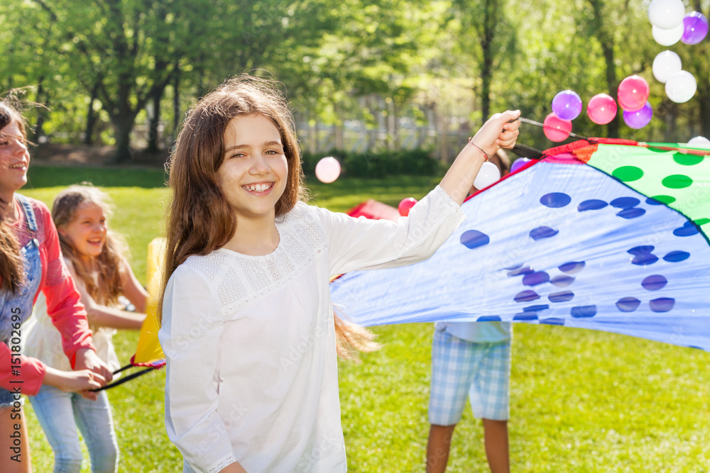 Happy girl playing colorful parachute in the park