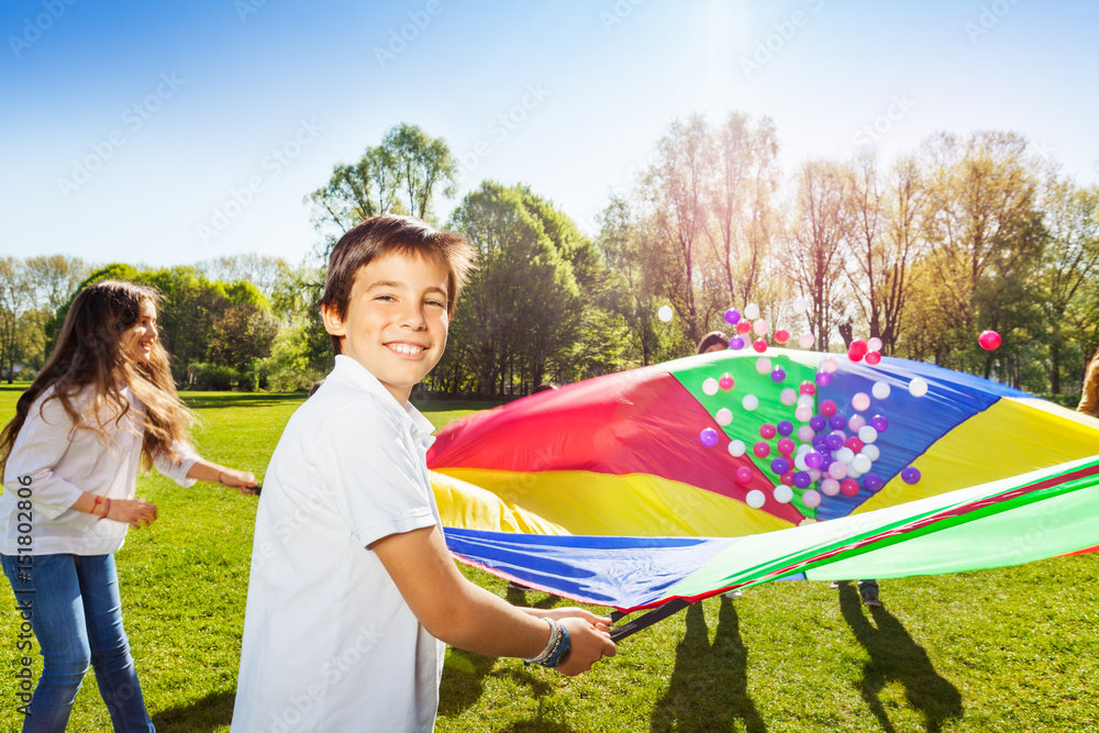 Happy boy holding parachute full of colorful balls