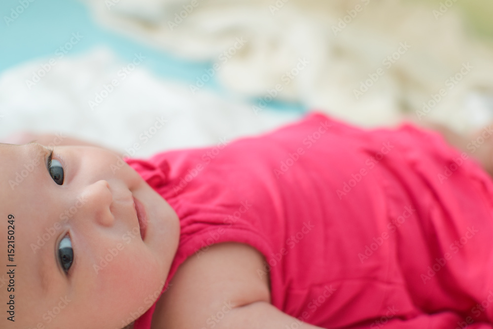 Beautiful cute newborn baby girl lying on her back wearing pink dress