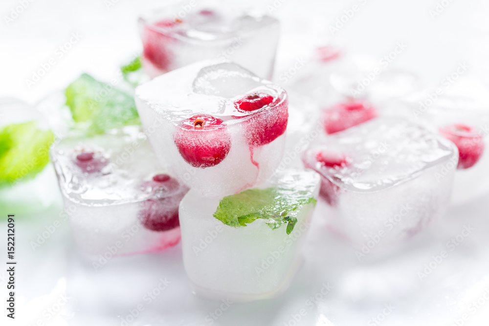 Ice cubes with berries and mint for summer drink on white background